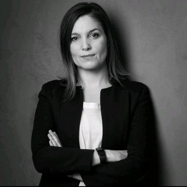 Cheffe d'entreprise en noir et blanc face à l'objectif et les bras croisés.