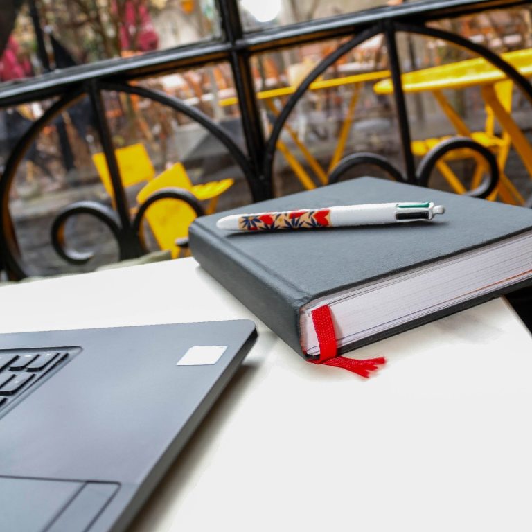 Carnet de notes et stylo aux côtés d'un ordinateur, outils essentiels pour organiser une stratégie numérique.